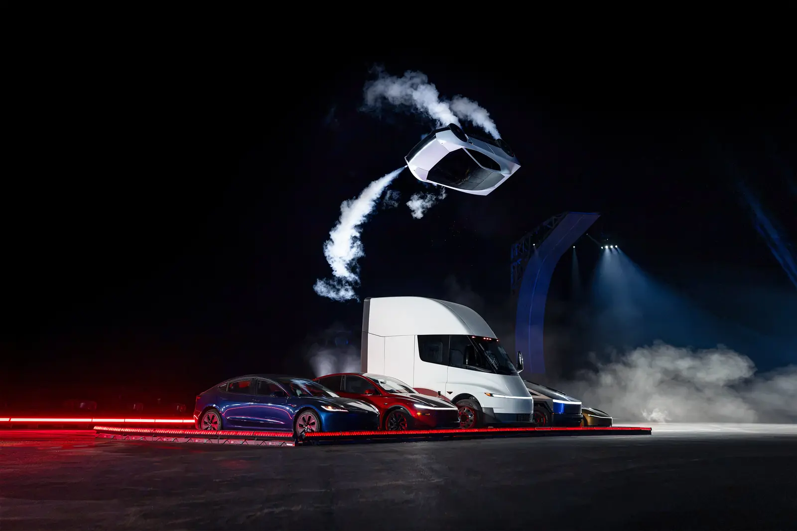 Tesla's next-gen Roadster flips midair on cold-gas thrusters above a Tesla Semi and Model 3 at its October 2026 reveal, a brand strategy halo moment